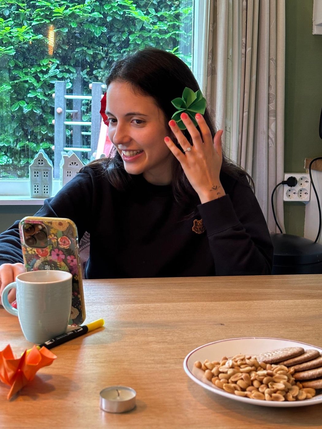 Smiling woman at a table with a mug and a plate of cookies and nuts